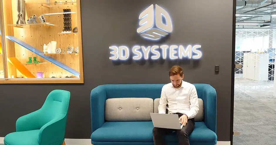 Ein Mann, der in einer Lounge bei 3D Systems sitzt und an seinem Laptop arbeitet