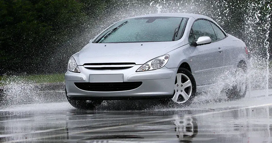 Ein Auto, das durch eine Pfütze fährt und einen riesigen Spritzer erzeugt