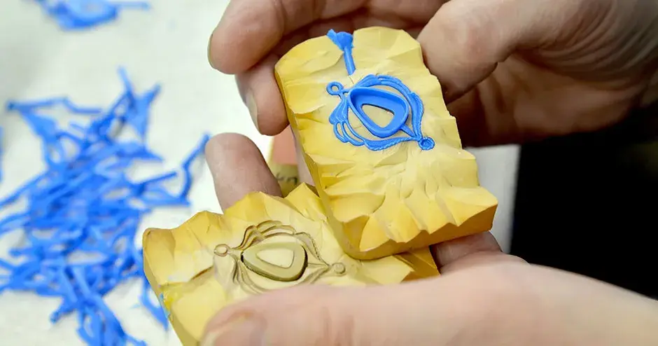 blauer wachsanhänger mit abgerundeter dreieckiger Lünette in gelber gummiform