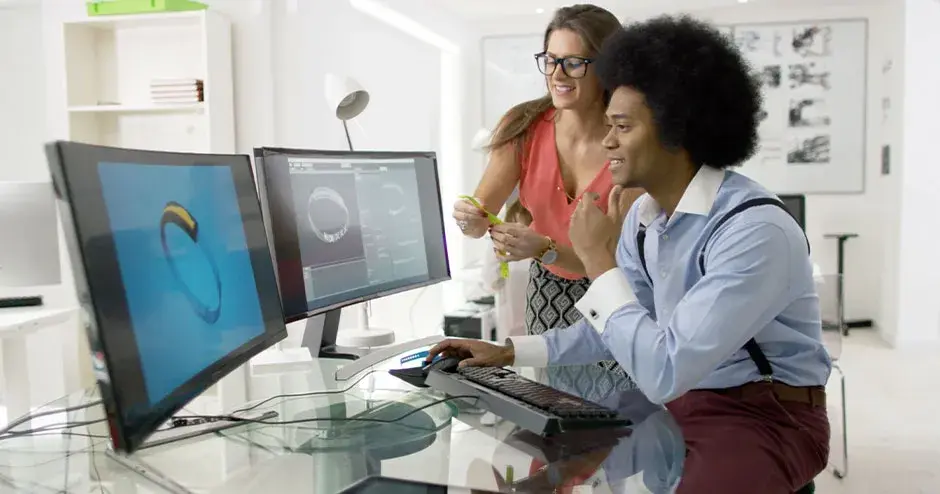 2 Personen, die eine Uhr entwerfen und die Datei auf einem großen Monitor bearbeiten