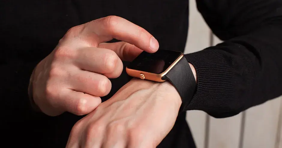 ein Mann, der eine Uhr trägt und auf die Merkmale der Uhr verweist