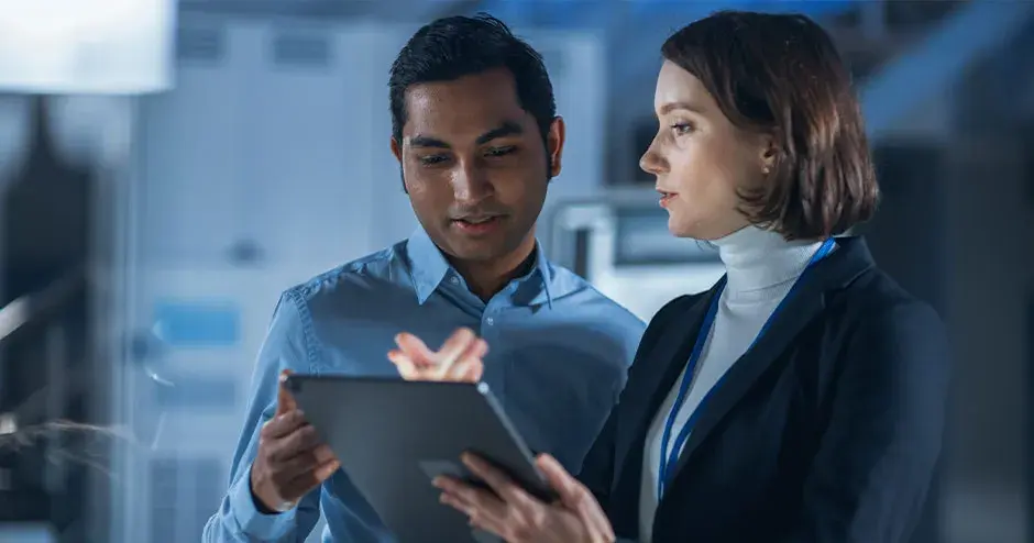 2 Personen, die in einer industriellen Umgebung zusammen an einem Tablett arbeiten